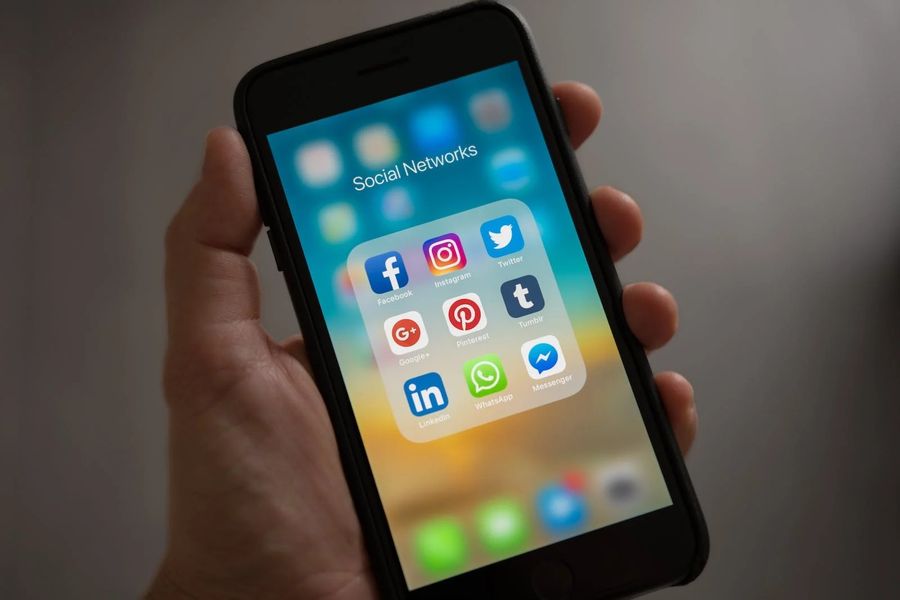 A hand holds a smartphone displaying a folder labeled Social Networks, showcasing app icons like Facebook, Instagram, and Twitter. Its tempting to dive in, but sometimes its wise to step away and take a break from the digital buzz.