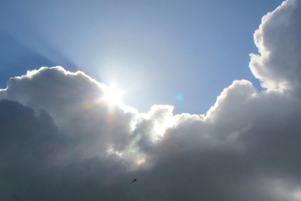 The sun peaks out from behind a dark cloud, creating a silver lining against a blue sky. Silver linings in emotional judgment can lead to clients feeling invalidated.